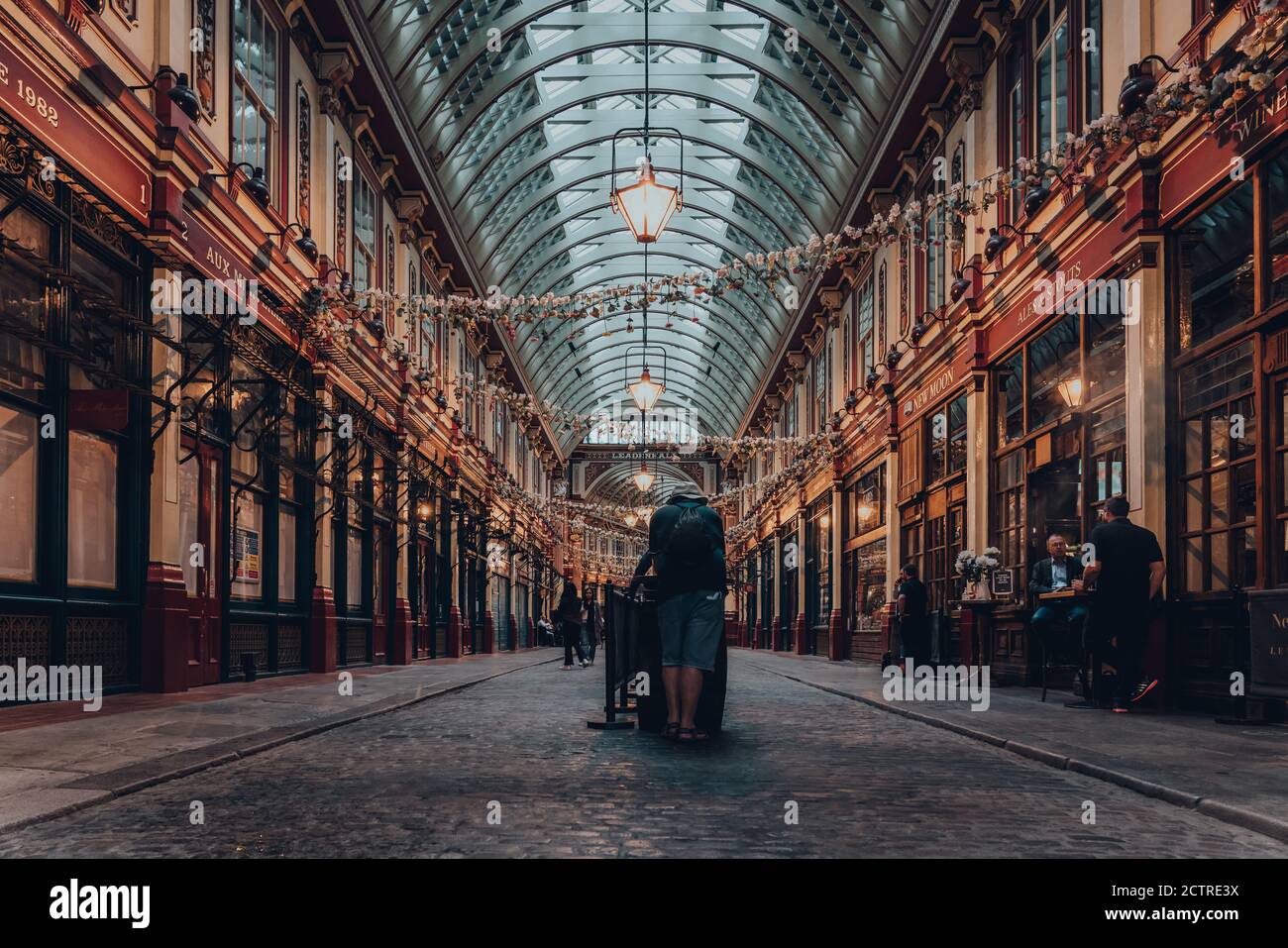 London, Großbritannien - 24. August 2020: Rückansicht eines Mannes, der allein an einem New Moon Pub Tisch in der Arkade des Leadenhall Market, einem beliebten Markt in London, steht Stockfoto