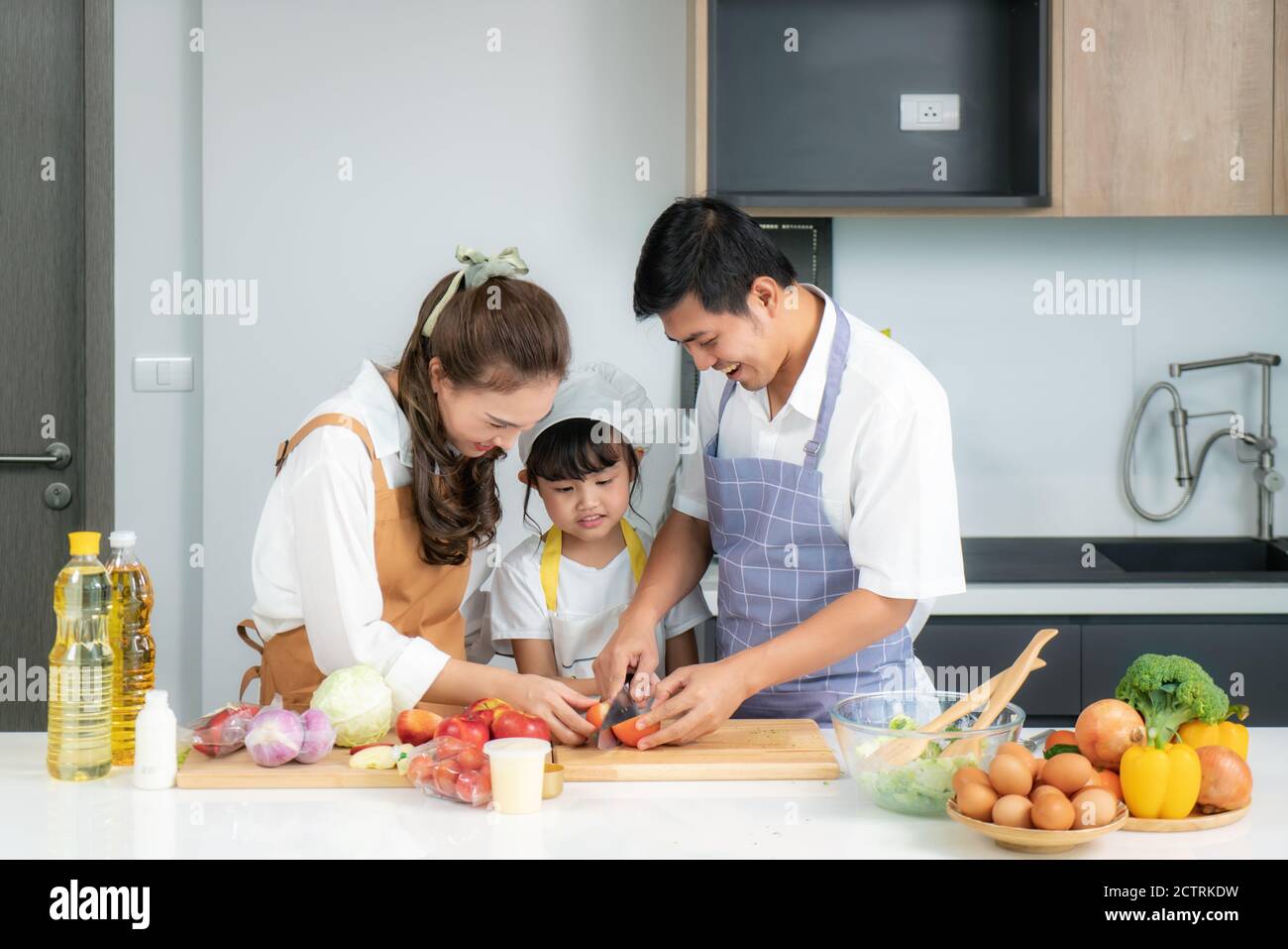 Junge asiatische Liebe Familie bereiten Salat Gemüse auf dem Tisch In der Küche, die Vater und Mutter lehren Tochter Kochen Essen am Tag um Stockfoto