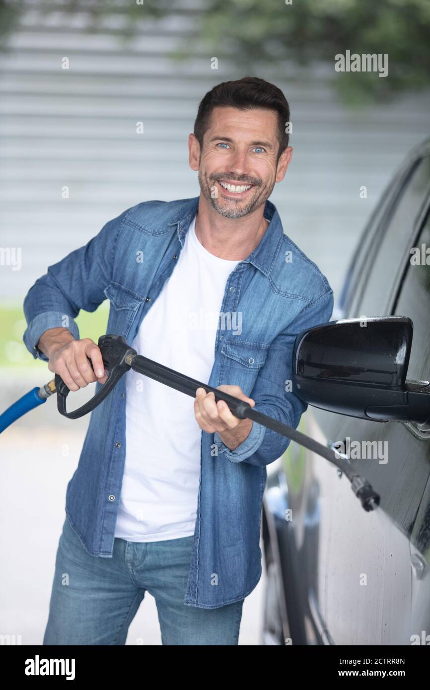 Glücklicher Mann, der ein Auto putzt Stockfoto