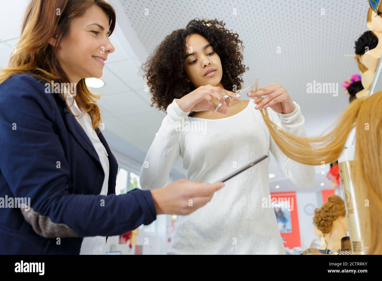 Friseurlehrling Schneiden von Kunsthaar Stockfoto