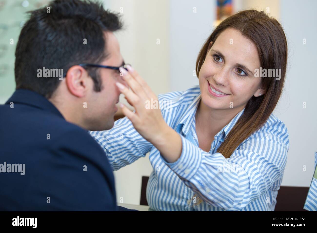 Augenoptiker, der Brillen auf männlichen Kunden einpasst Stockfoto