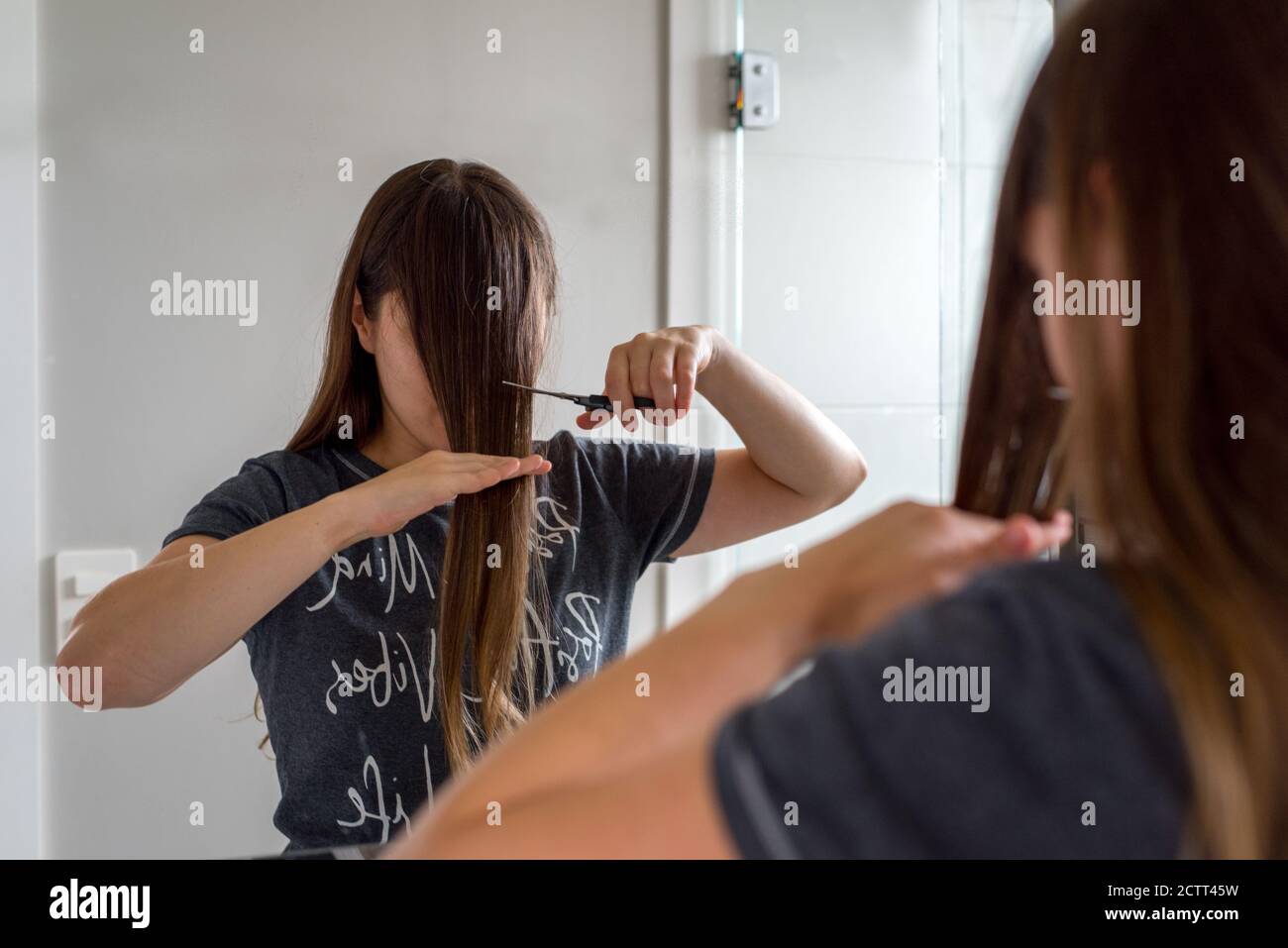 Frau mit langen braunen Haaren schneiden ihre eigenen Pony Stockfoto