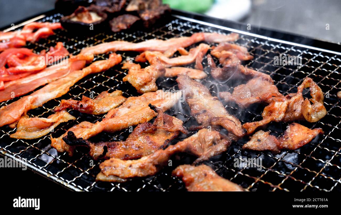 Holzkohlegrill von marinierten Schweinestreifen mit Raucheffekt Stockfoto