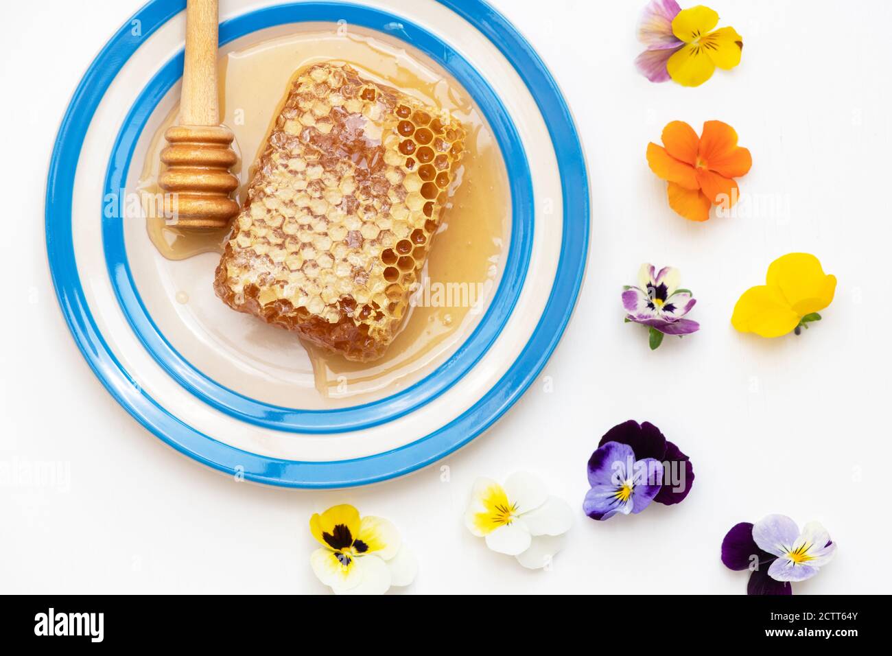 Wabe auf einem Maisgeschirr Teller mit einem Niesler und essbar Blumen Stockfoto