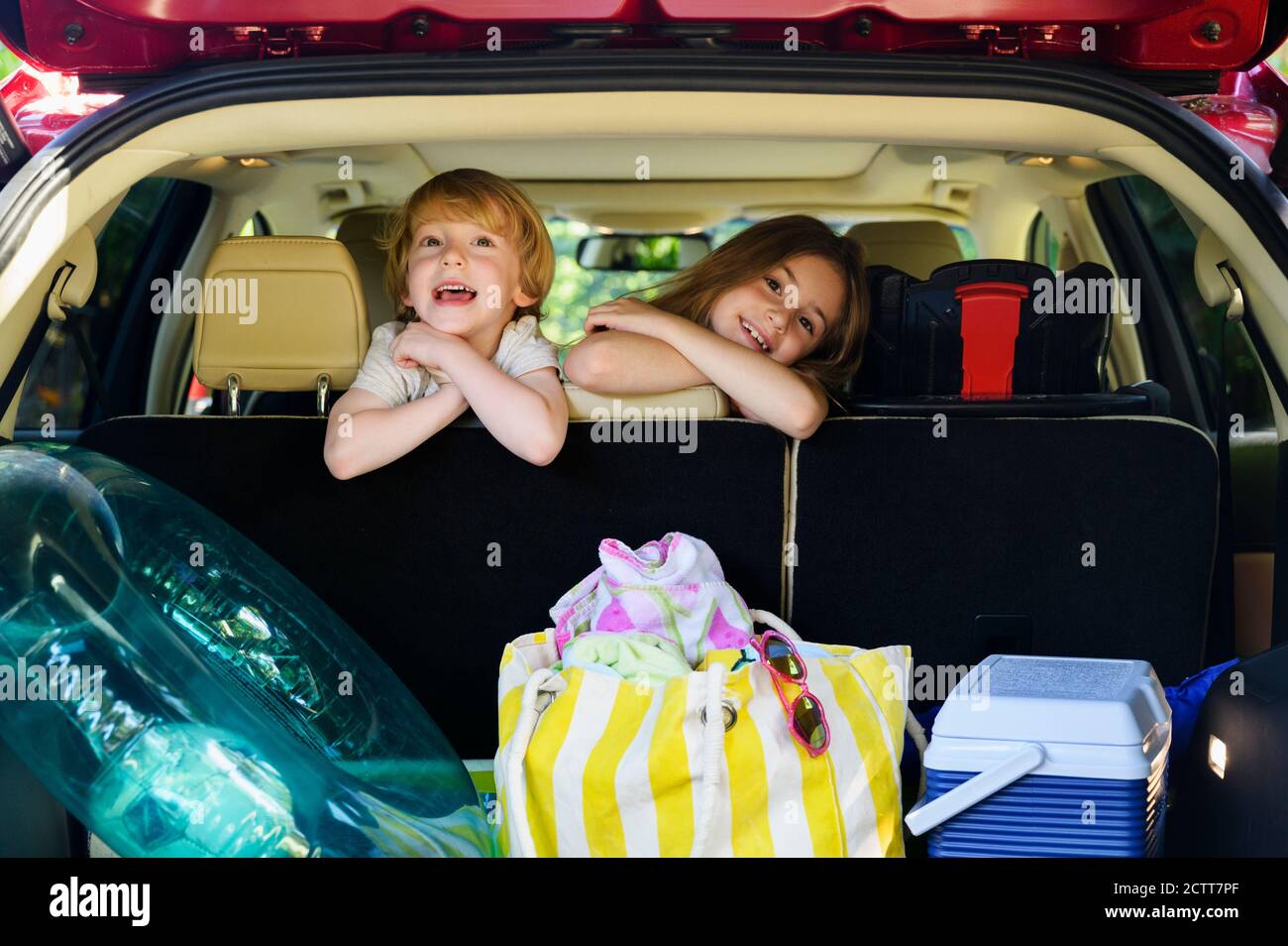 Junge (4-5) und Mädchen (6-7) sitzen im Auto bereit für Urlaubsreise Stockfoto