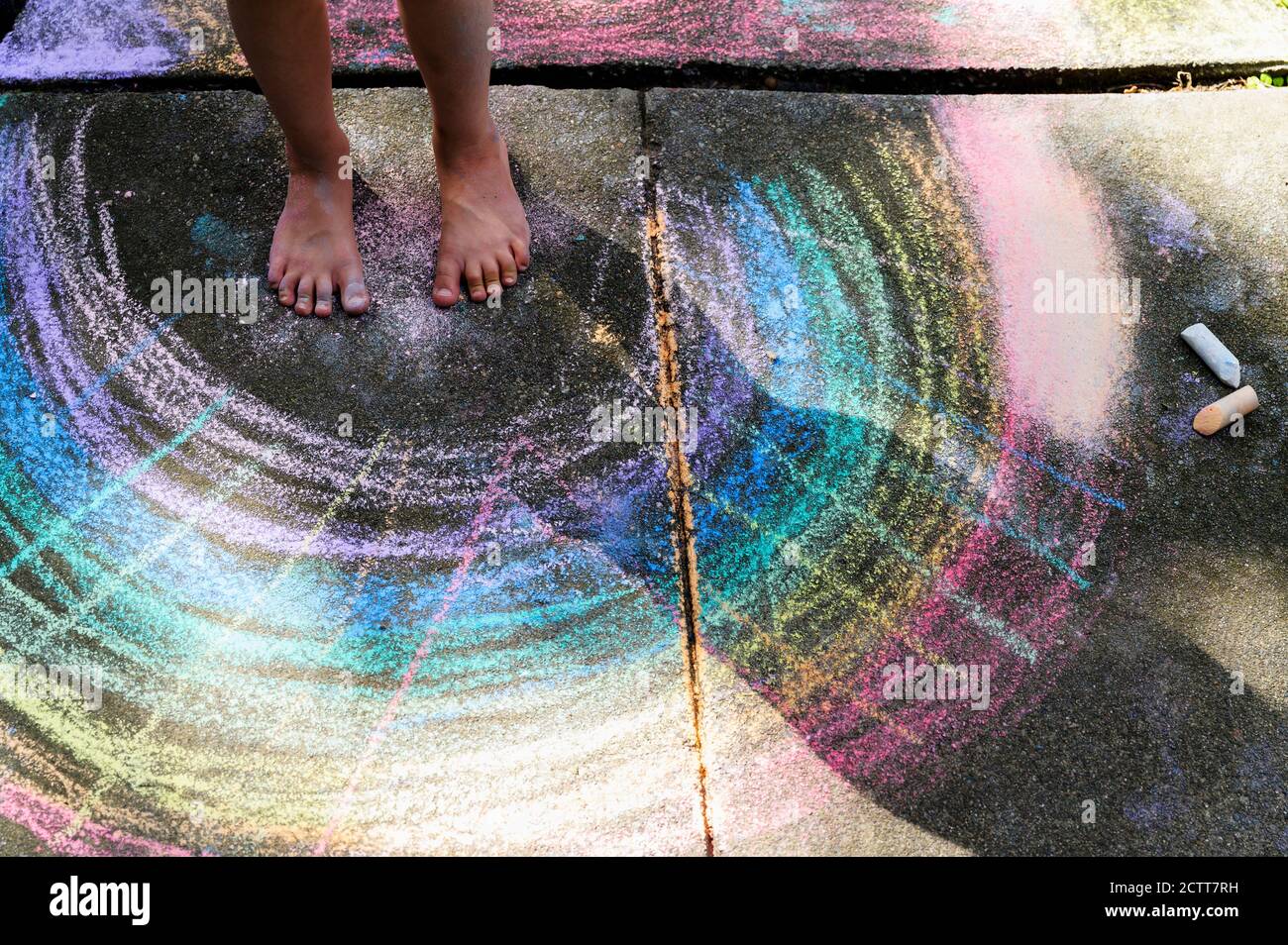 Unterer Schnitt des Mädchens (6-7), das auf der Kreidezeichnung steht Gehweg Stockfoto