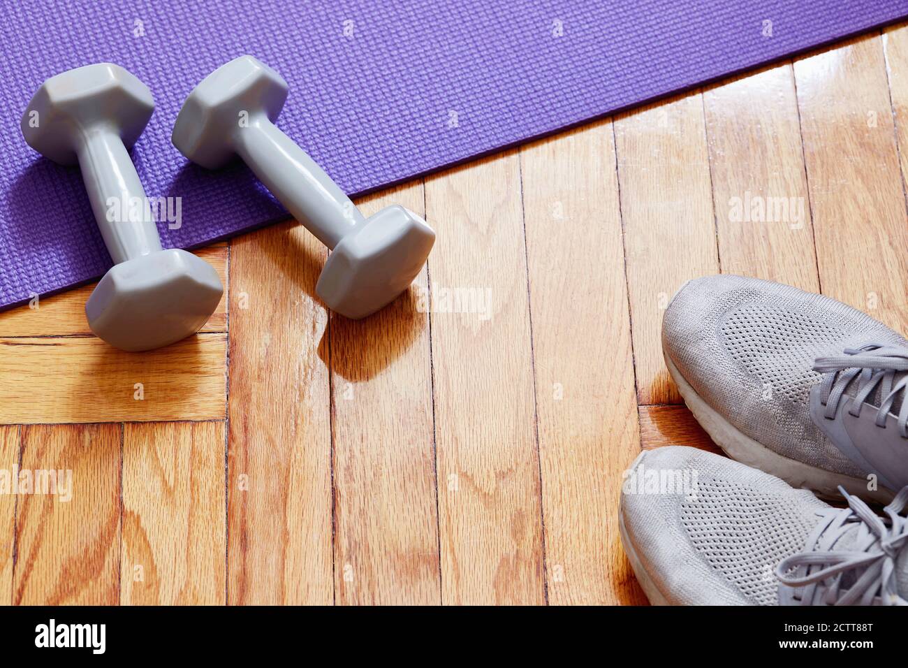 Gewichte, Yogamatte und Laufschuhe auf dem Boden Stockfoto