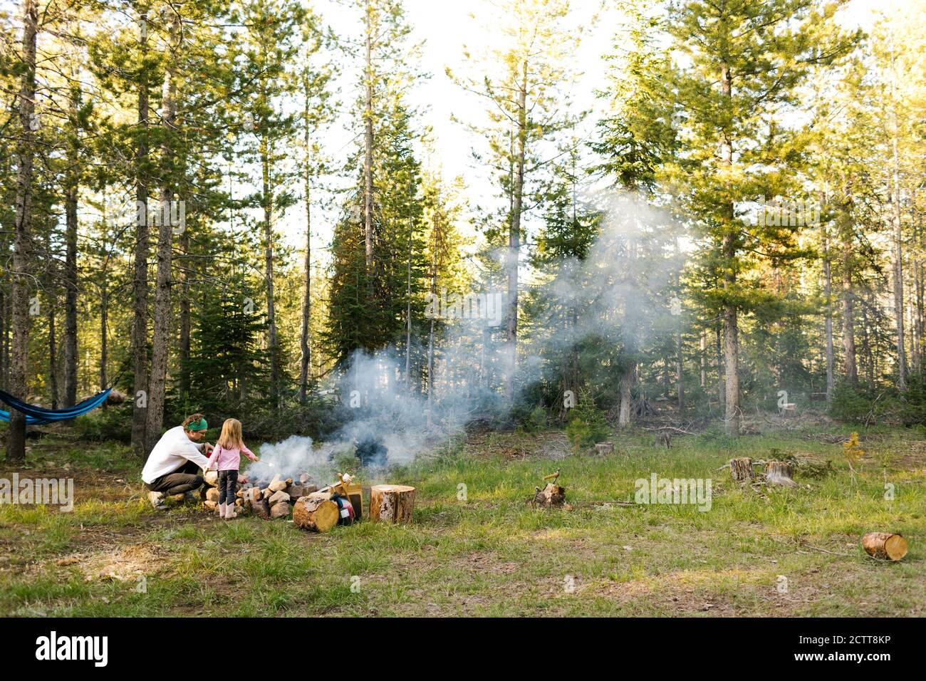 Vater und Tochter (4-5) am Lagerfeuer im Wald, Wasatch Cache National Forest Stockfoto