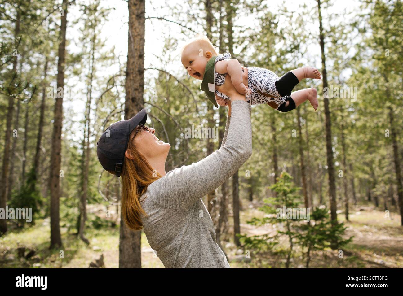 Lächelnde Frau, die mit einem kleinen Sohn (6-11 Monate) im Wald, Wasatch-Cache National Forest, spielt Stockfoto