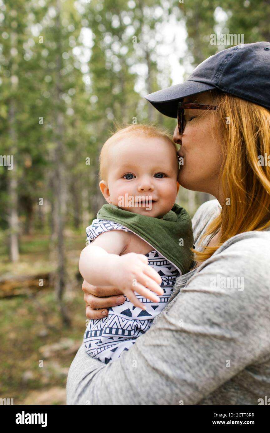 Frau küsst Baby-Sohn (6-11 Monate) im Wald, Wasatch-Cache National Forest Stockfoto