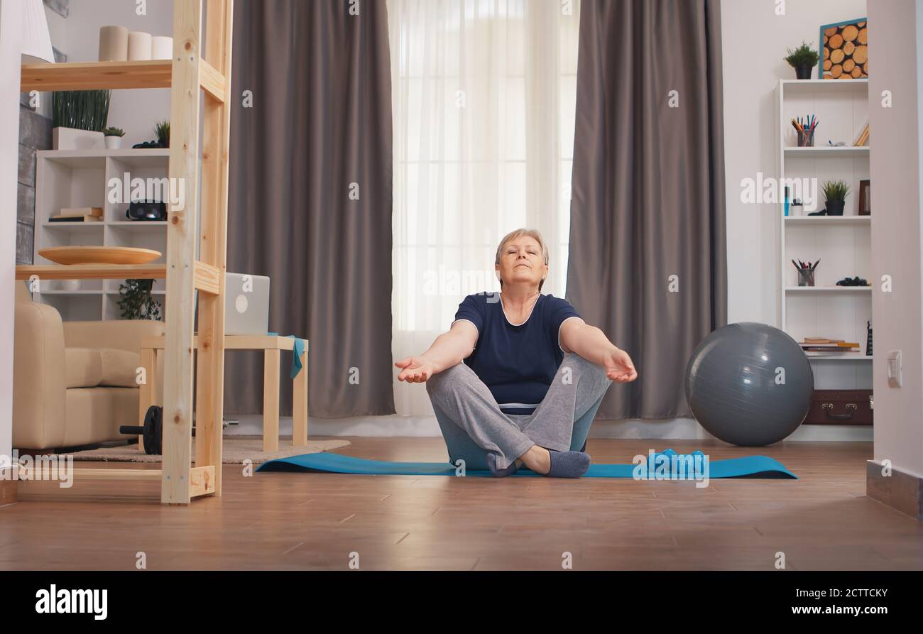 Ältere Frau, die sich im Wohnzimmer entspannt und Yoga macht. Aktiv gesund Lifestyle sportlich Old Person Training Training Home Wellness und Indoor-Training Stockfoto