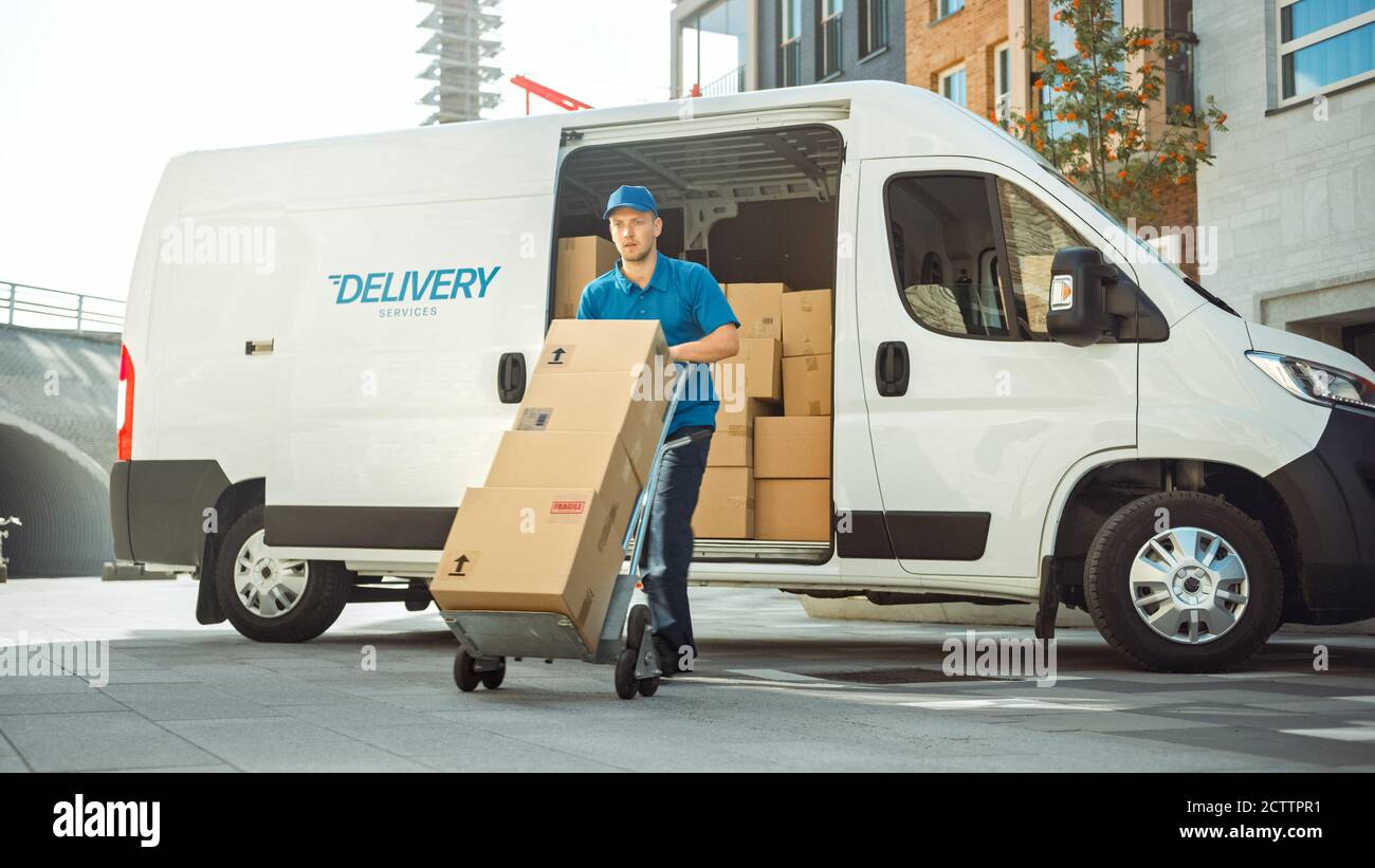 Delivery man schiebt Hand Truck Trolley voll von Karton-Boxen Hände Paket an einen Kunden. Courier liefert Paket an man im Business District. Stockfoto