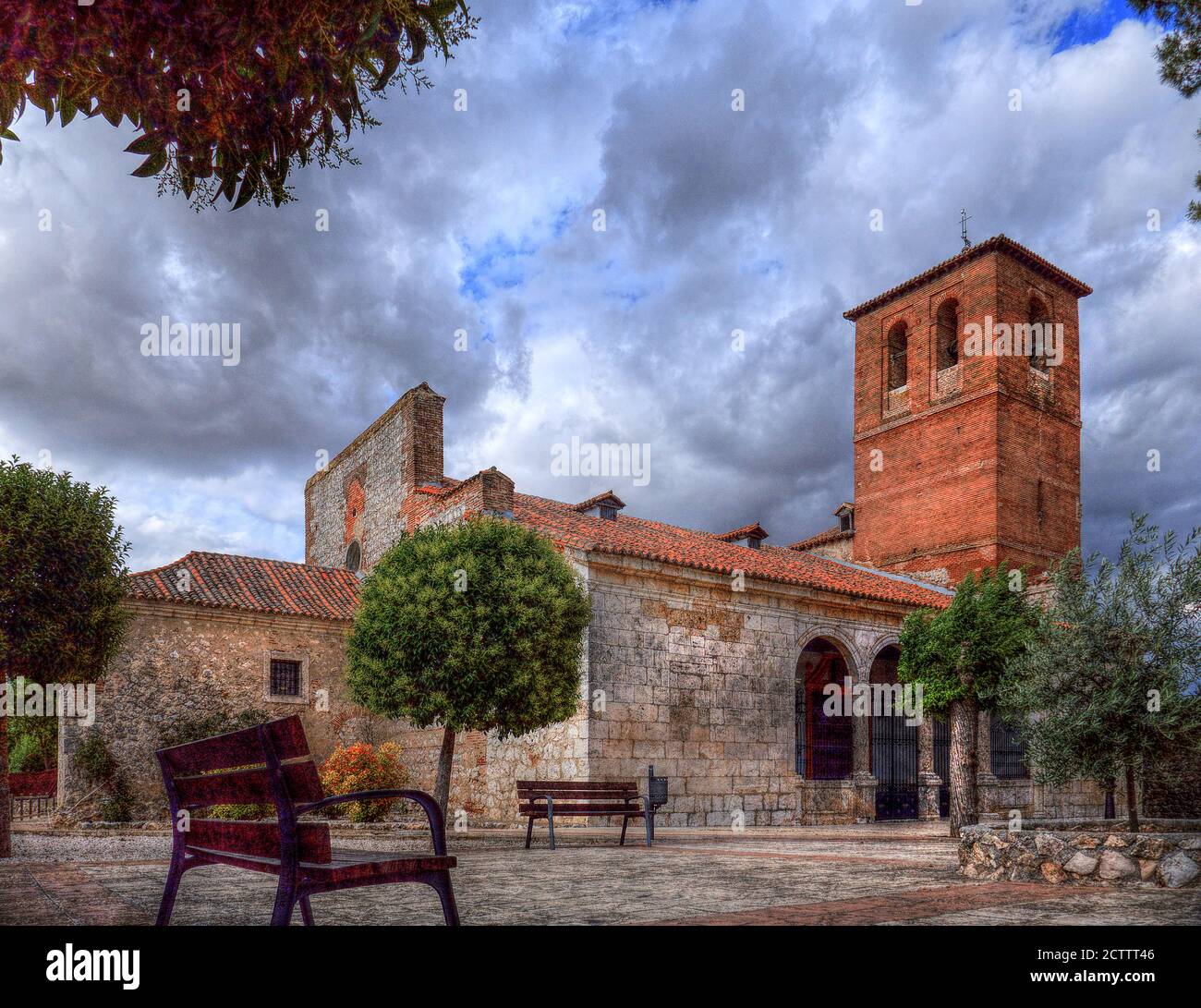 Romanische Kirche aus dem 18. Jahrhundert mit beeindruckendem Turm auf der piazza mit dramatischen Wolken in Spanien Stockfoto