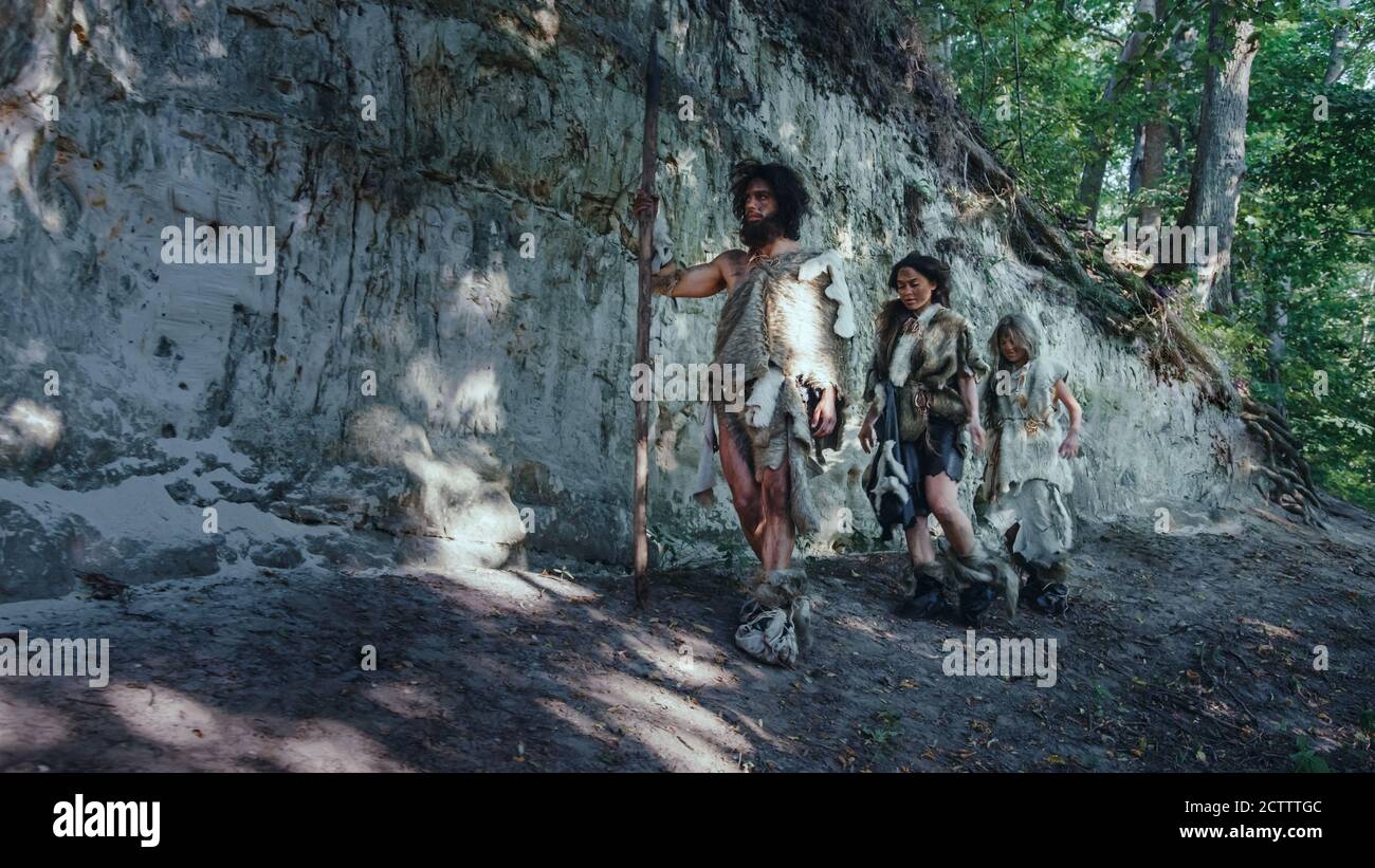 Stamm der Jäger und Sammler tragen Tierhaut Leben in einer Höhle. Lebensmittel Vorbereiten, Lagerfeuer Bauen, Henkel Verstecken, Arbeiten, Jagd. Frohes Neanderthal Stockfoto