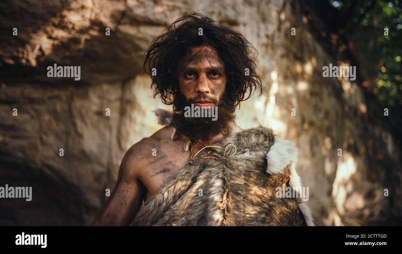 Portrait des uralten Höhlenmenschen mit Tierhaut Holding Stein getippten Hammer. Prähistorische Neanderthal Hunter posiert mit primitiven Jagd in der Stockfoto