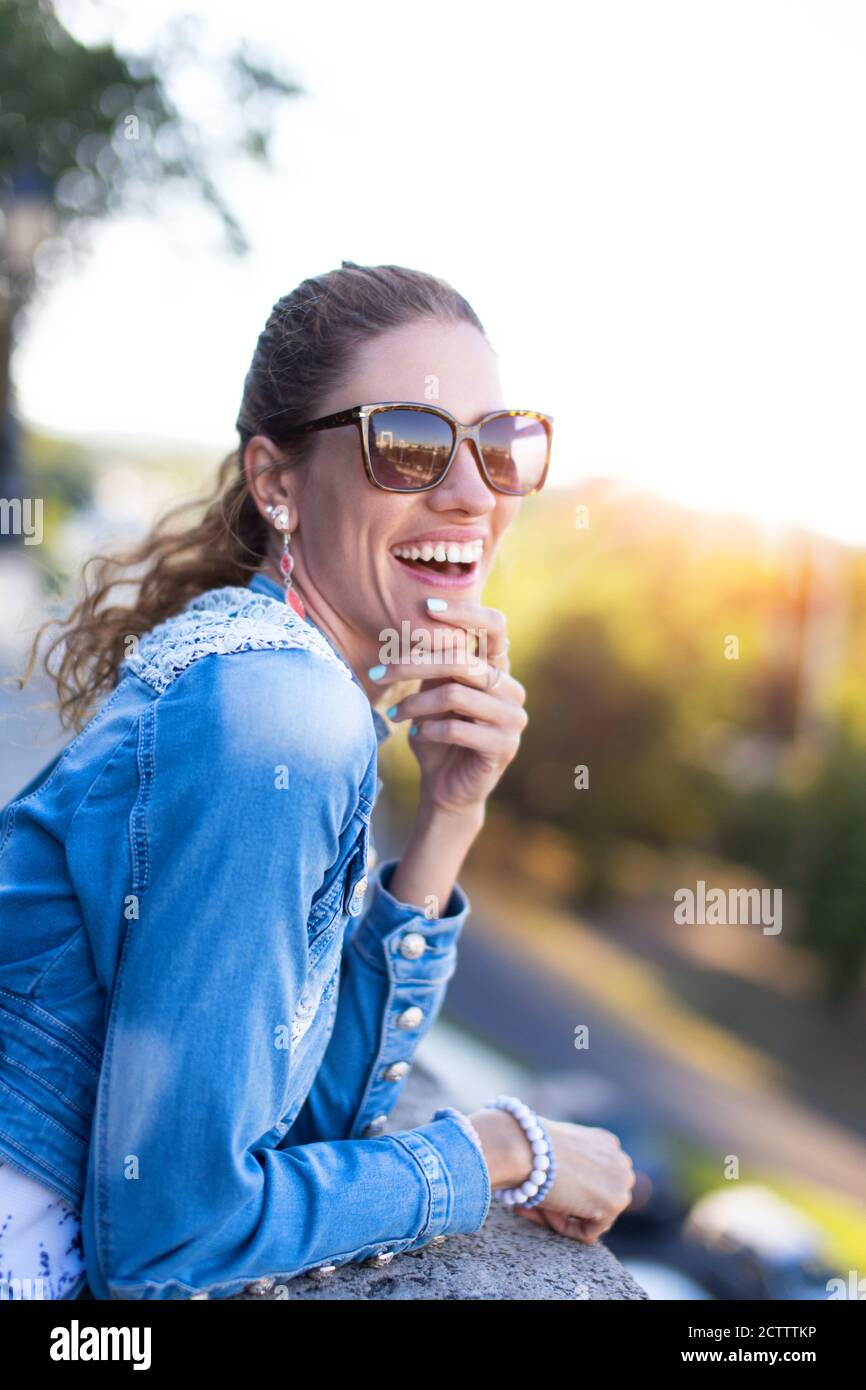 Glückliche 30s Stadtfrau lachend im Park auf Witze, gute Laune Stockfoto