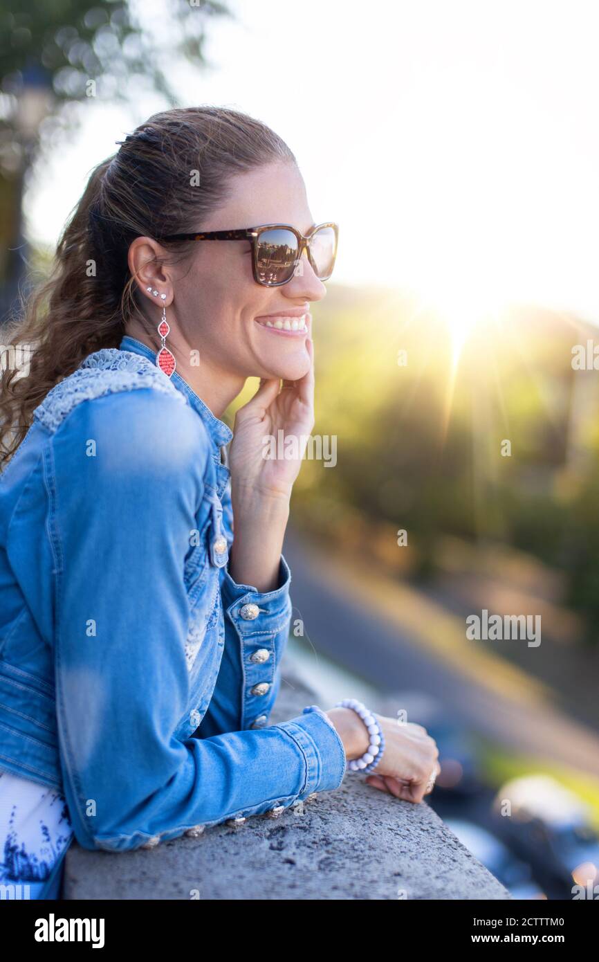 Ausgewogene junge kaukasische Frau toothy Lächeln im Sonnenuntergang im Park Stockfoto