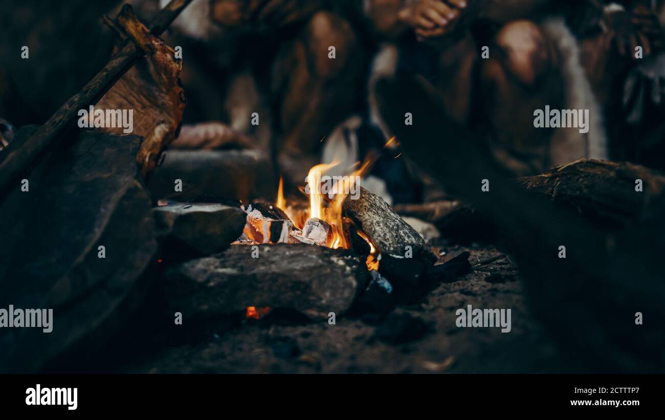 Nahaufnahme von Tribe Prähistorische Jäger und Sammler versuchen, sich am Bonfire warm zu werden, Hände über Feuer halten, Essen kochen. Neandertaler oder Homo Sapiens Stockfoto