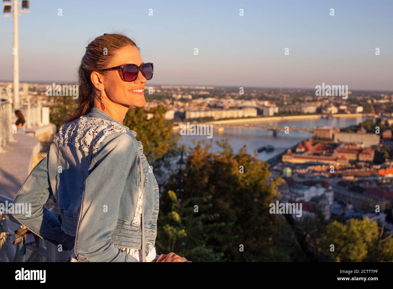 Junge Stadtfrau wundert sich im Stadtpanorama, oranger Sonnenuntergang Stockfoto