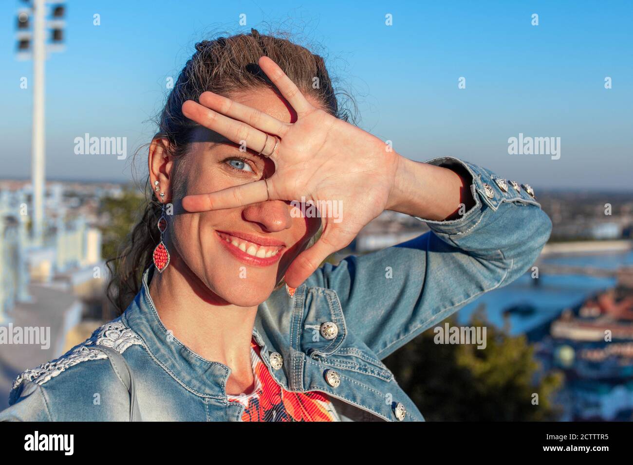 Lustige junge Frau bedeckt ihr Gesicht mit der Hand in Sonnenschein, im Freien Stockfoto