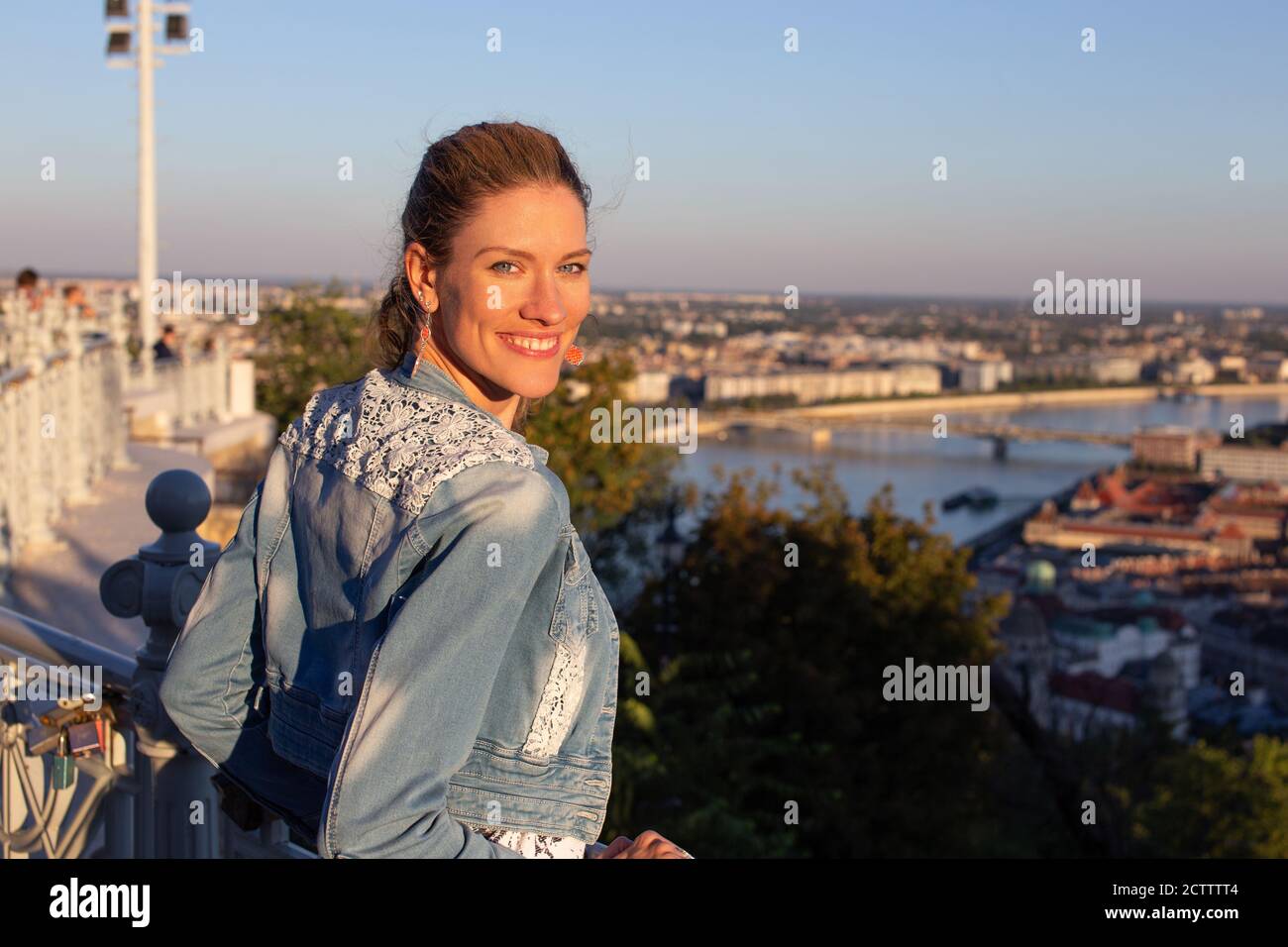 Heitere junge urbane Frau, die in den Sonnenuntergang zurückblickt, Budapest, Ungarn Stockfoto