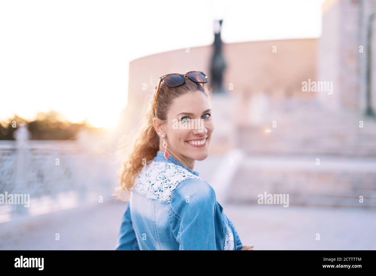 Glückliche junge kaukasische Frau Blick zurück auf berühmten Ort, Porträt, toothy Lächeln Stockfoto