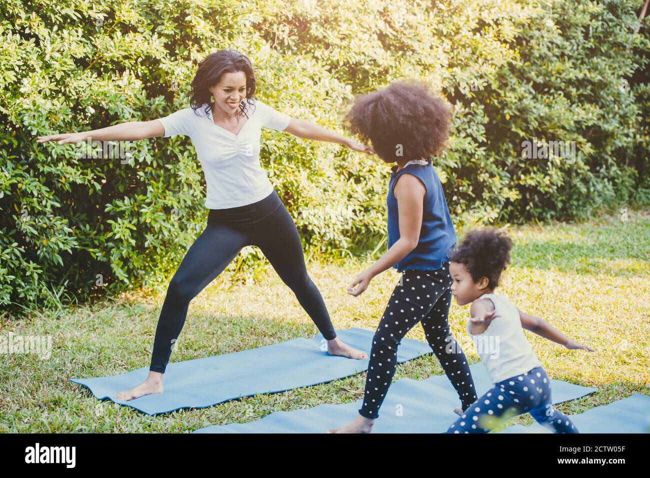 Schwarze afroamerikanische Mutter mit Kind, das Yoga-Familienaktivität zusammen am Hinterhof während der Selbstquarantäne zu Hause spielt. Stockfoto