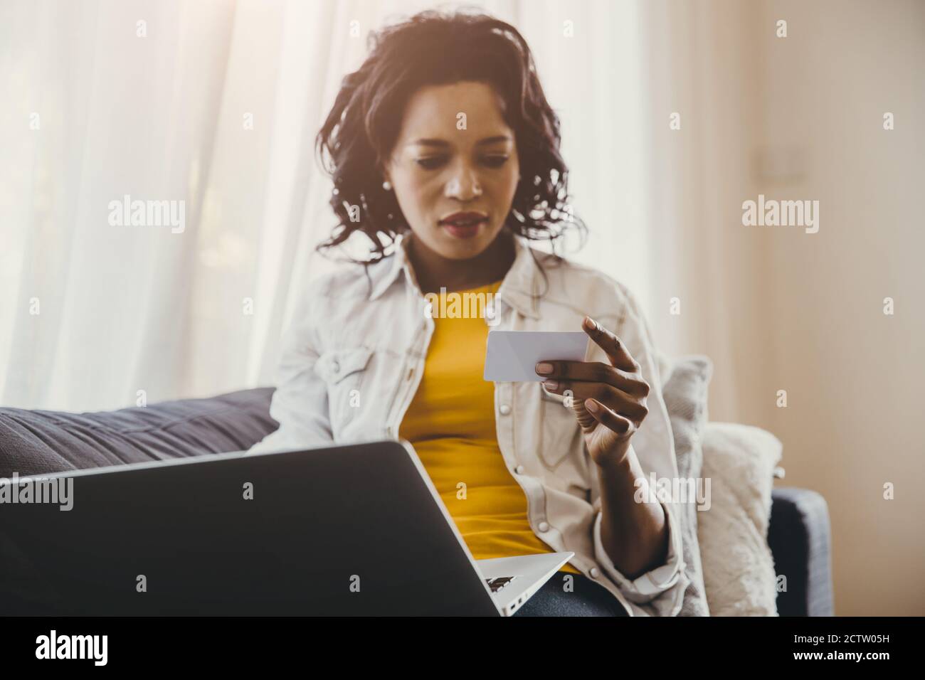 Afrikanische oder Schwarze Menschen Hand und Blick auf Visitenkarte oder Kreditkarte mit Laptop-Computer-Suche zu Hause oder Online-Shopping-Konzept. Stockfoto