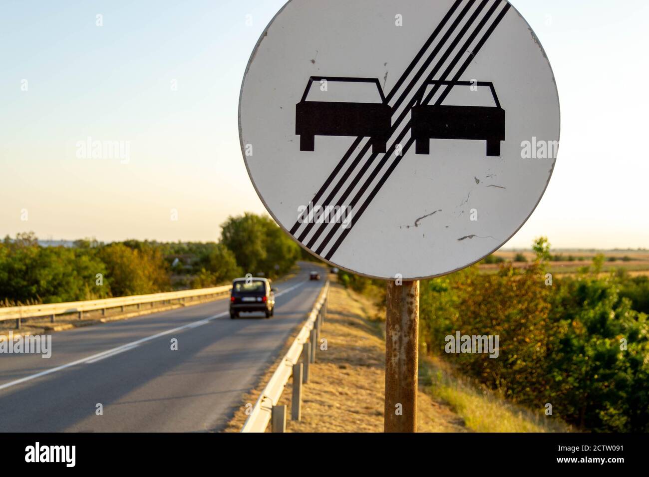 Schild 'Überholen Sie nicht', mit der Straße im Hintergrund Stockfoto