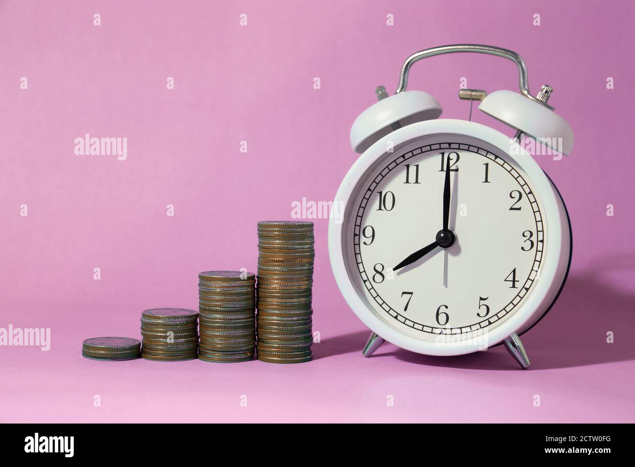 Münzstapel mit Wecker mit süßen rosa Raum Hintergrund für Zeiten, Geld zu sparen Konzept gestapelt. Stockfoto