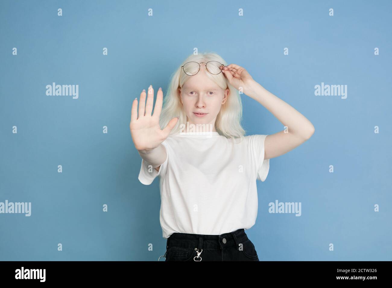 Stopp. Nahaufnahme Porträt der schönen kaukasischen Albino Mädchen isoliert auf blau. Blonde weibliche Modell mit stilvollen Look. Konzept des Gesichtsausdrucks, menschliche Emotionen, Kindheit, Werbung, Verkauf, Vielfalt. Stockfoto