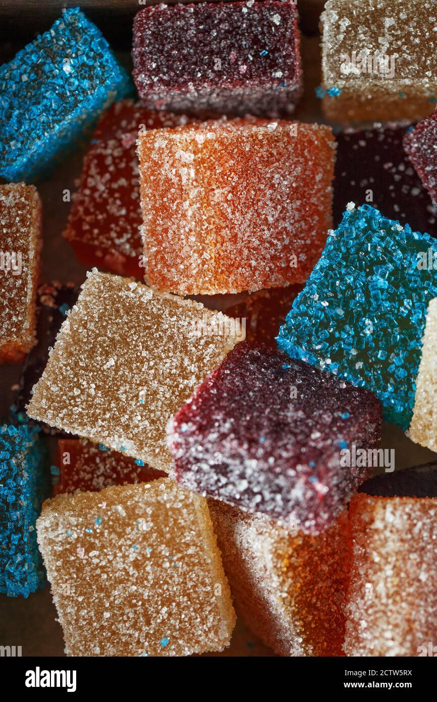 Hausgemachte bunte Marmelade Süßigkeiten in Zucker auf dunklem Hintergrund. Fruchtgelee Süßigkeiten. Obst Kaubonbons. Jelly Bean. Sortiment von bunten Früchten j Stockfoto