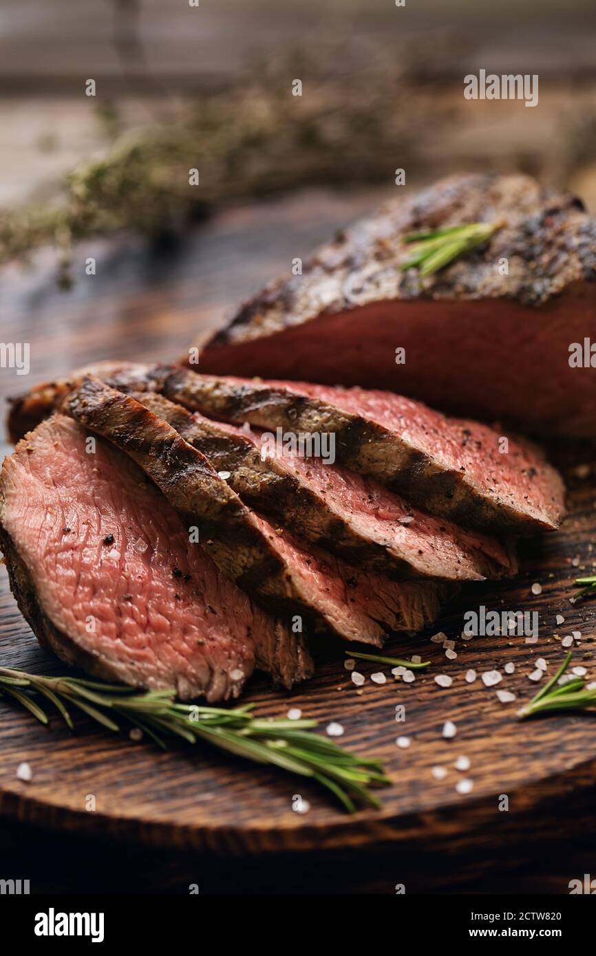 Saftig Medium Beef Rib Eye Steak Scheiben auf Holzbrett mit Kräutern Gewürze und Salz. Fertig zum Essen Steak mit Zutaten auf einem Schneidebrett. Stockfoto