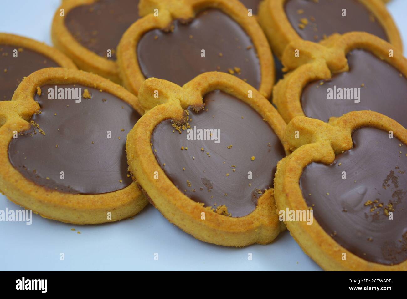 Frische leckere knusprige Shortbread-Kekse mit nussiger Schokoladenfüllung im Inneren. Apfelförmige Kekse mit brauner Füllung auf einer weißen Matte. Stockfoto