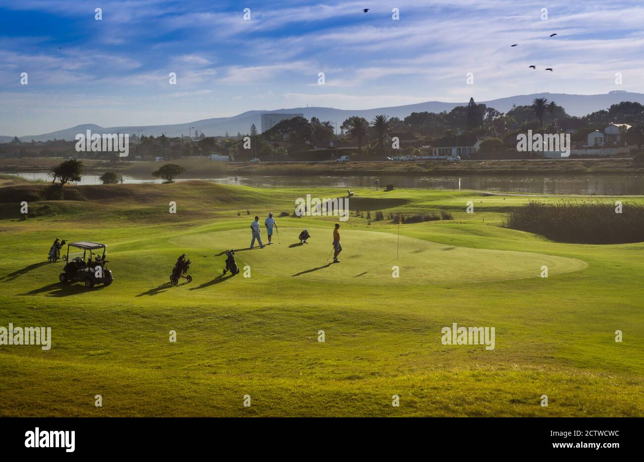Golfer spielen Golf auf einer grünen Wiese mit einer Lagune im Hintergrund,  Kapstadt, Südafrika Stockfotografie - Alamy