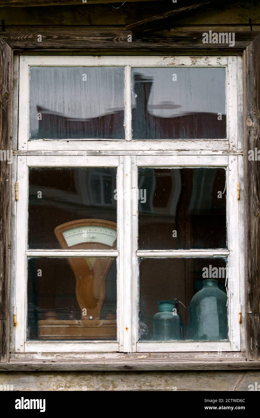 Ein altes Holzfenster in einem Haus mit Objekten, die durch das Glas sichtbar sind und auf der Fensterbank stehen. Stockfoto