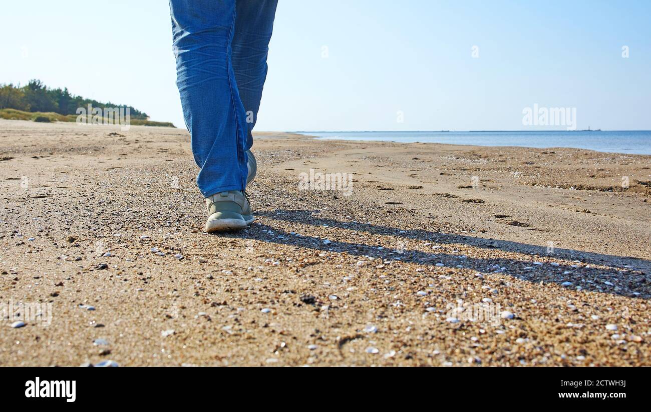 Nahaufnahme eines Männerfußes, der am Meer entlang läuft Der Strand Stockfoto