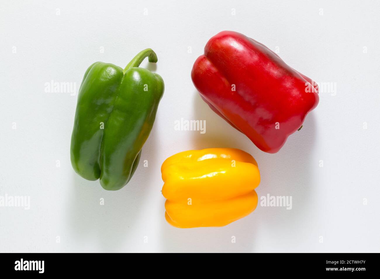 Drei rote, grüne und gelbe Paprika auf weißem Hintergrund Stockfoto