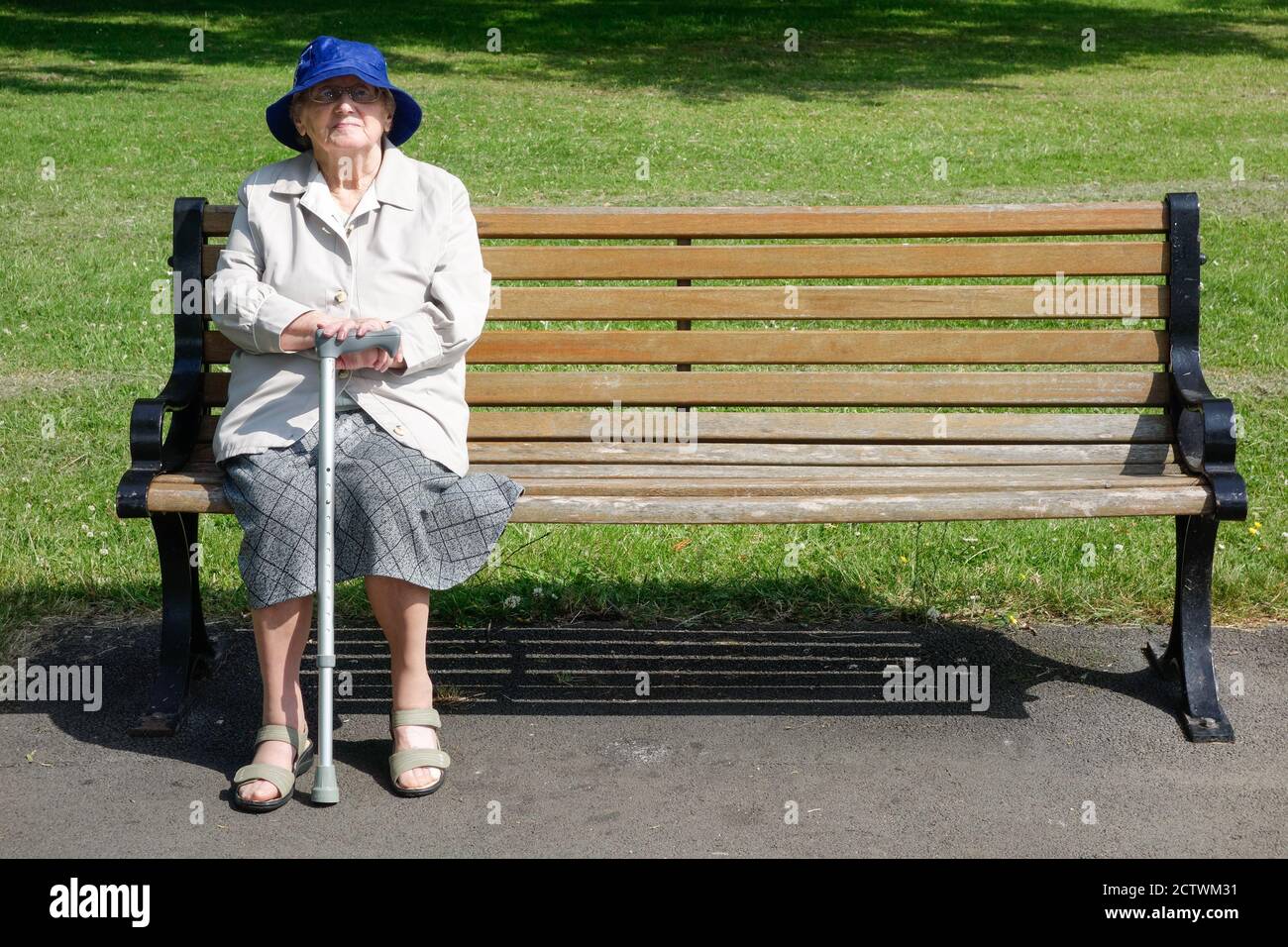 Neunzig Jahre alte Frau mit Spazierstock sitzt auf Parkbank. VEREINIGTES KÖNIGREICH Stockfoto