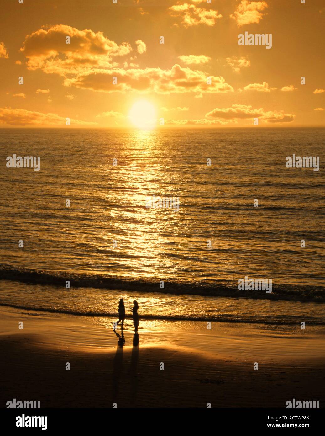 Männliche und weibliche Silhouetten treffen sich am romantischen Sonnenuntergangsstrand Stockfoto