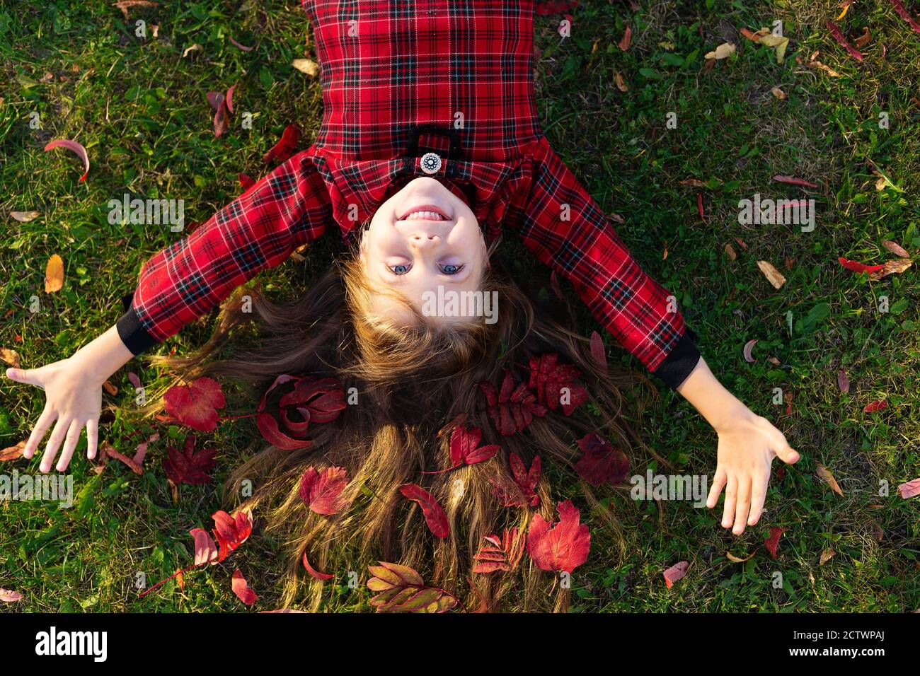Ein schönes Mädchen liegt auf dem Boden mit Herbstblättern im Haar. Stockfoto