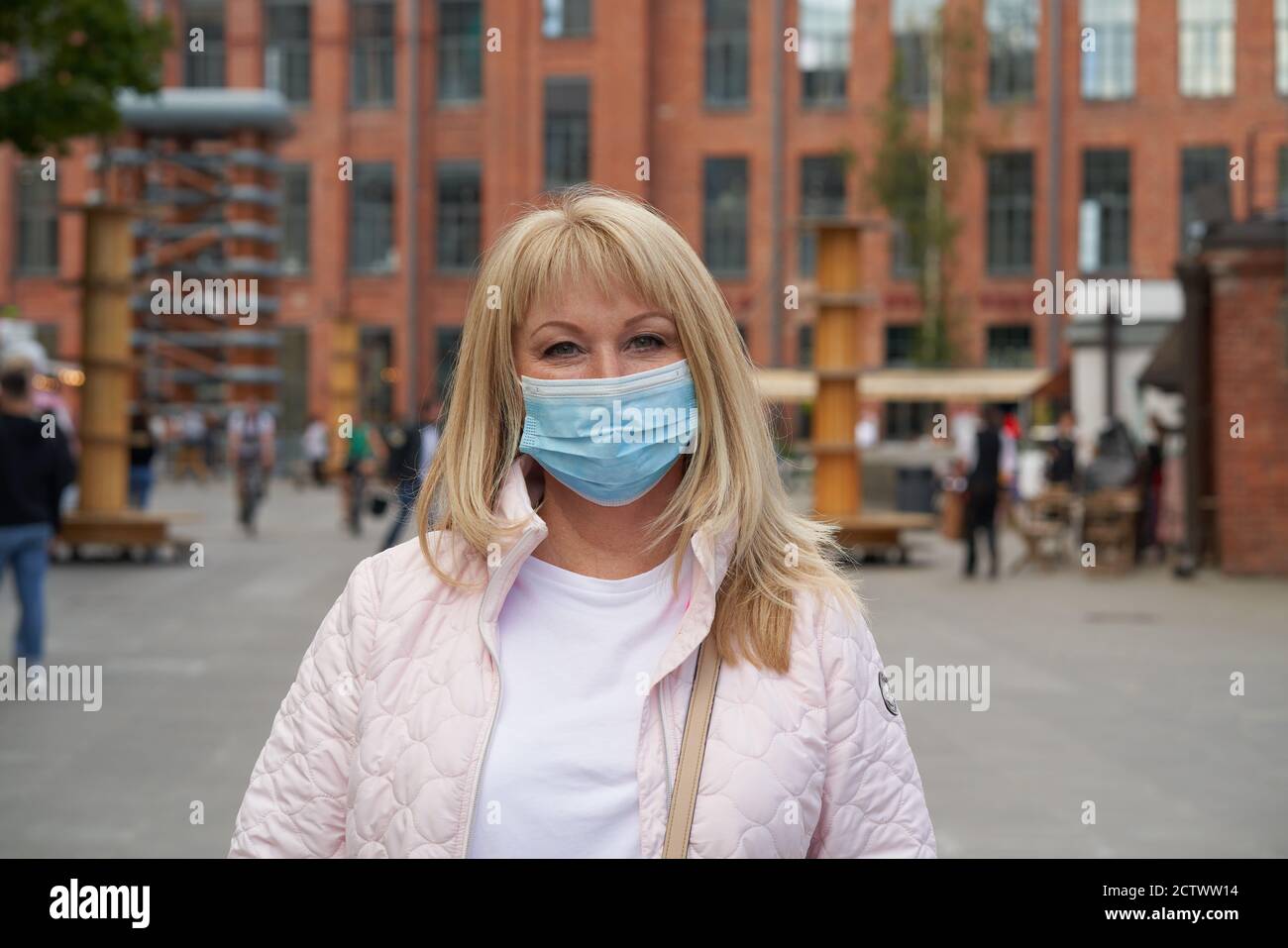 Frau in schützende medizinische Gesichtsmaske draußen in der Öffentlichkeit stehen Ort Stockfoto