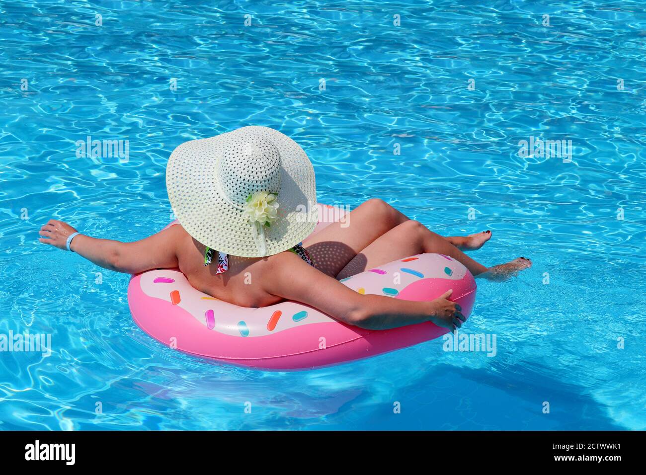 Frau in Hut und Bikini Schwimmen auf aufblasbaren Donut Ring im Pool. Strandurlaub, Entspannung und Freizeitkonzept Stockfoto