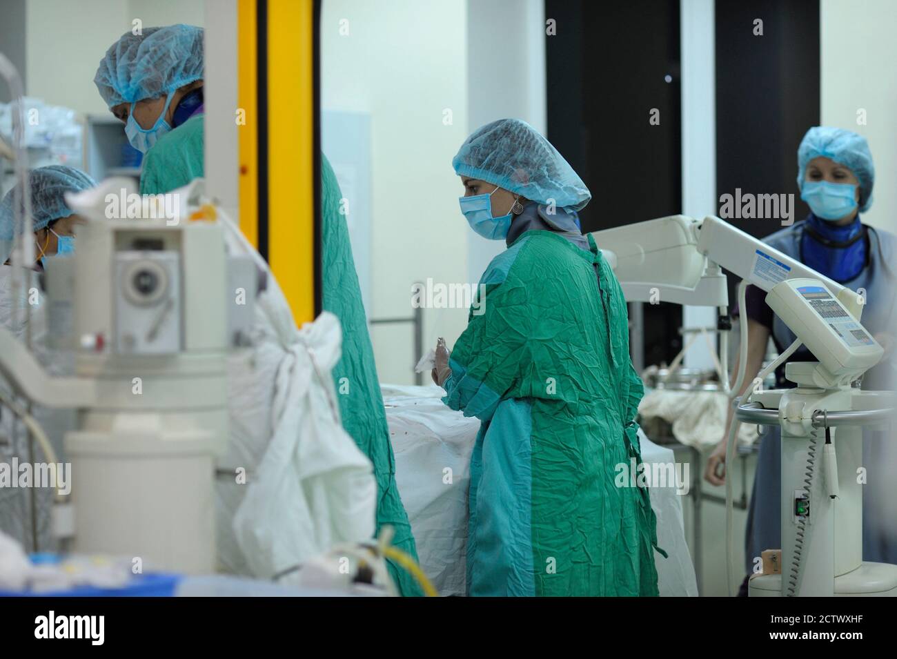 Im Operationssaal. Weibliche Chirurgen in der Maske über Gesicht in der Nähe der Patientenplatte stehen und desinfizieren Hände. Ukrainisches Kinderkardienzentrum Stockfoto