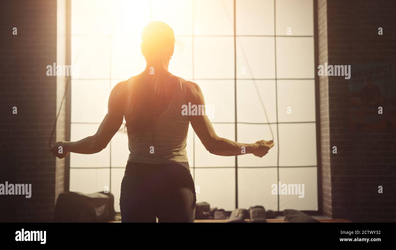 Starke Athletic Frau Übungen mit Springseil in einem Loft-Stil Industrial Gym. Sie konzentriert sich auf ihr intensives Cross Fitness Trainingsprogramm Stockfoto