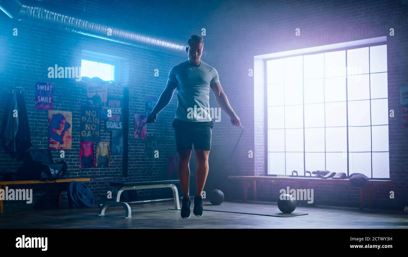 Maskuline Athletic Young man Übungen mit Jumping Rope in einem Loft-Stil Industrial Gym. Er macht sein intensives Cross Fitness Trainingsprogramm Stockfoto