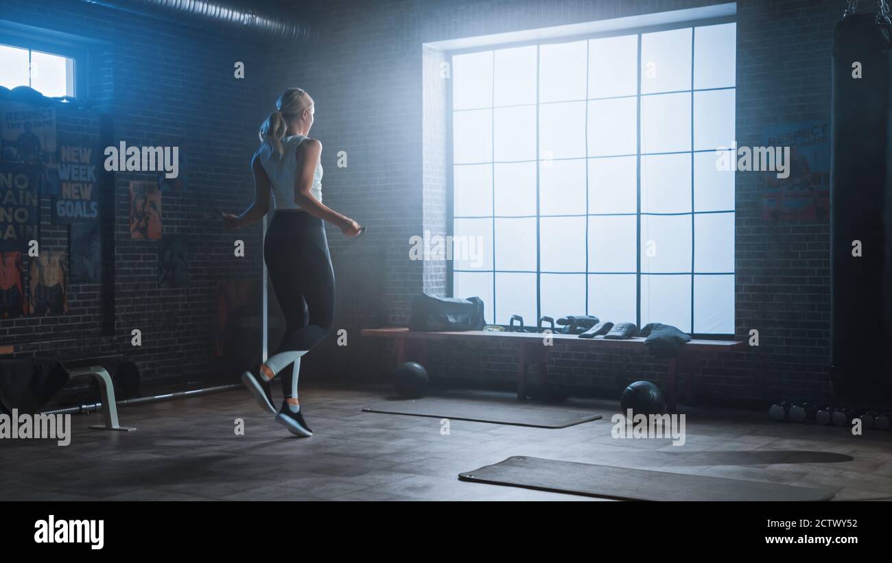 Fit Athletic Blonde Frau Übungen mit Springseil in einem Loft-Stil Industrial Gym. Sie Macht Ihr Intensives Cross Fitness Trainingsprogramm. Anlage hat Stockfoto