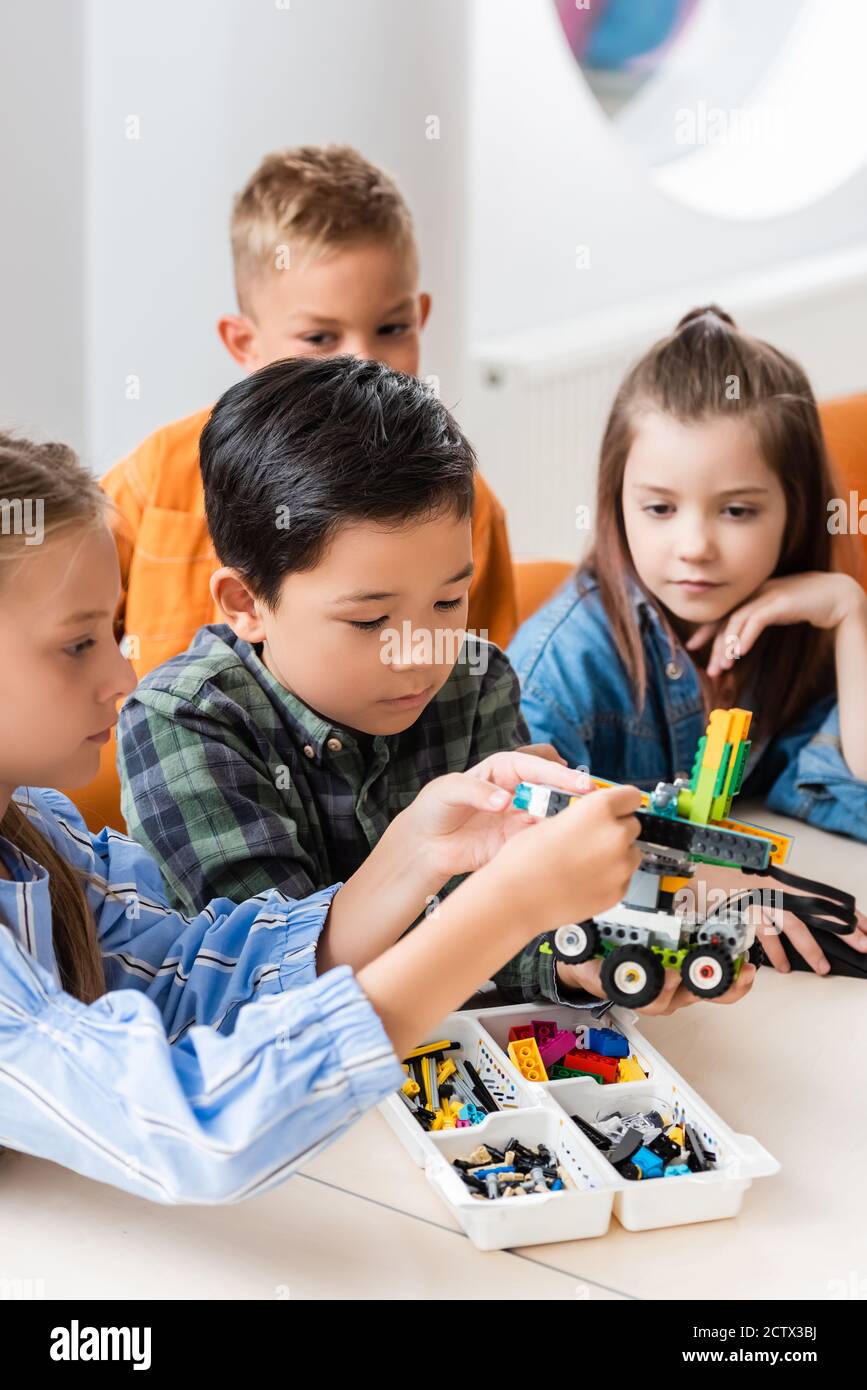 Selektiver Fokus von multiethnischen Kindern mit Bausteinen Modellierung Roboter In der MINT-Schule Stockfoto