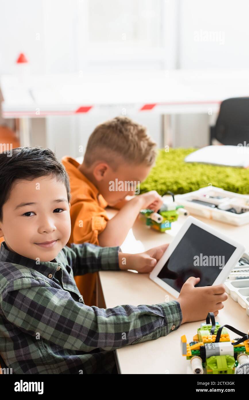 Selektive Fokus der asiatischen Schuljunge halten digitale Tablette in der Nähe Freund Modellierroboter in der MINT-Schule Stockfoto