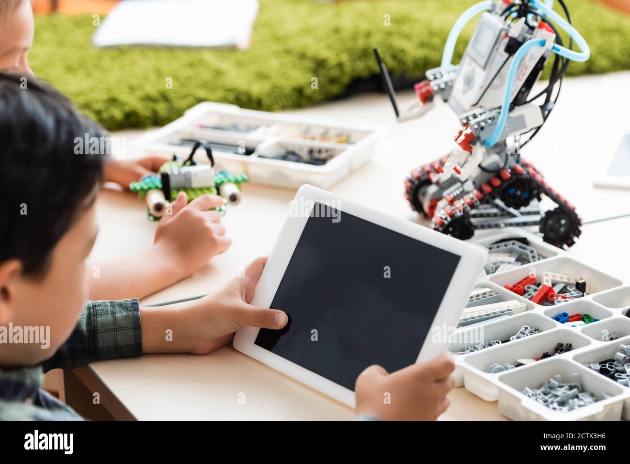 Selektive Fokussierung multiethnischer Schüler mit digitalem Tablet beim Bauen Roboter im Klassenzimmer Stockfoto